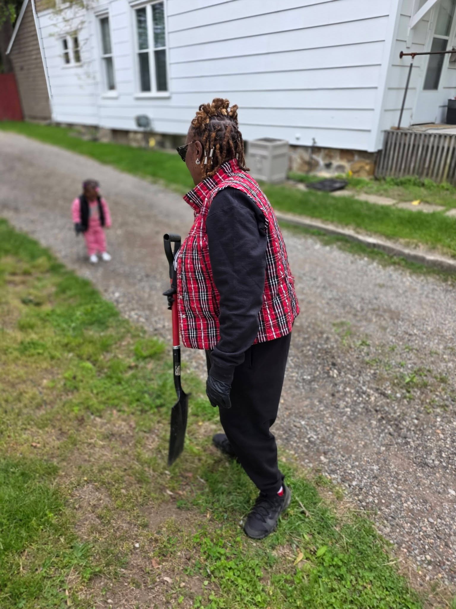 A volunteer in a red plaid vest helping with the grounds during Community Impact Day