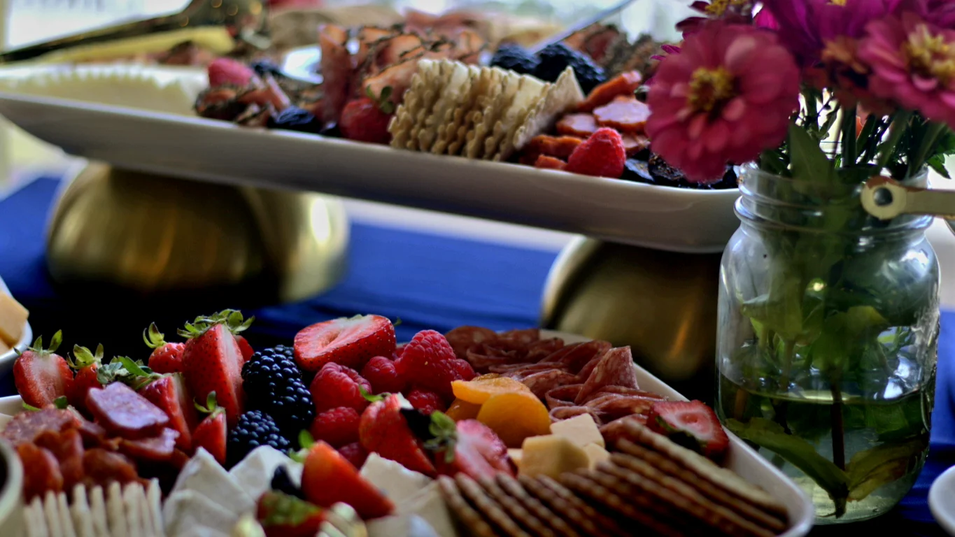 Fruit and grazing platters arranged alongside fresh flowers.