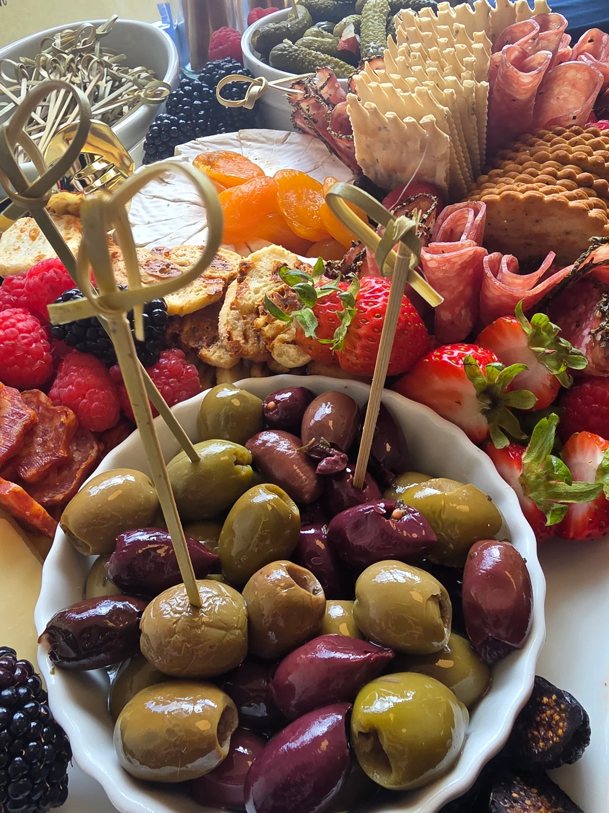 Olives, berries, cheese, and crackers fill a generous grazing platter.